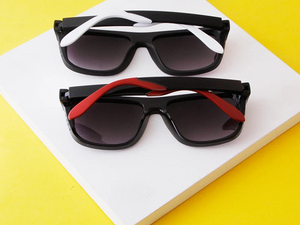 a pair of black and white sunglasses sitting on top of a yellow surface